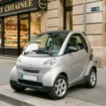 Chatenet 4 places garée devant une boulangerie française, vue trois quarts avant de la microvoiture sans permis en argent métallisé