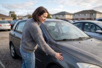 Jeune femme examine une voiture d'occasion en extérieur