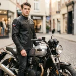 Jeune motard avec permis A2 debout à côté de sa moto dans une rue urbaine pavée