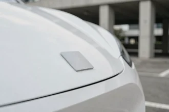 Emblème minimaliste et plat d'une marque automobile sur la calandre d'un véhicule électrique blanc, illustrant la simplification des logos de constructeurs