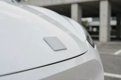 Emblème minimaliste et plat d'une marque automobile sur la calandre d'un véhicule électrique blanc, illustrant la simplification des logos de constructeurs